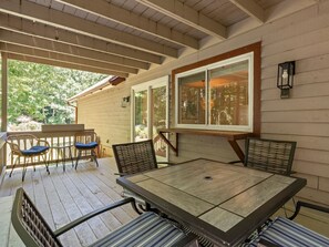 Eine überdachte Terrasse mit einem Holztisch und Stühlen, großen Fenstern und Blick auf Grünflächen.