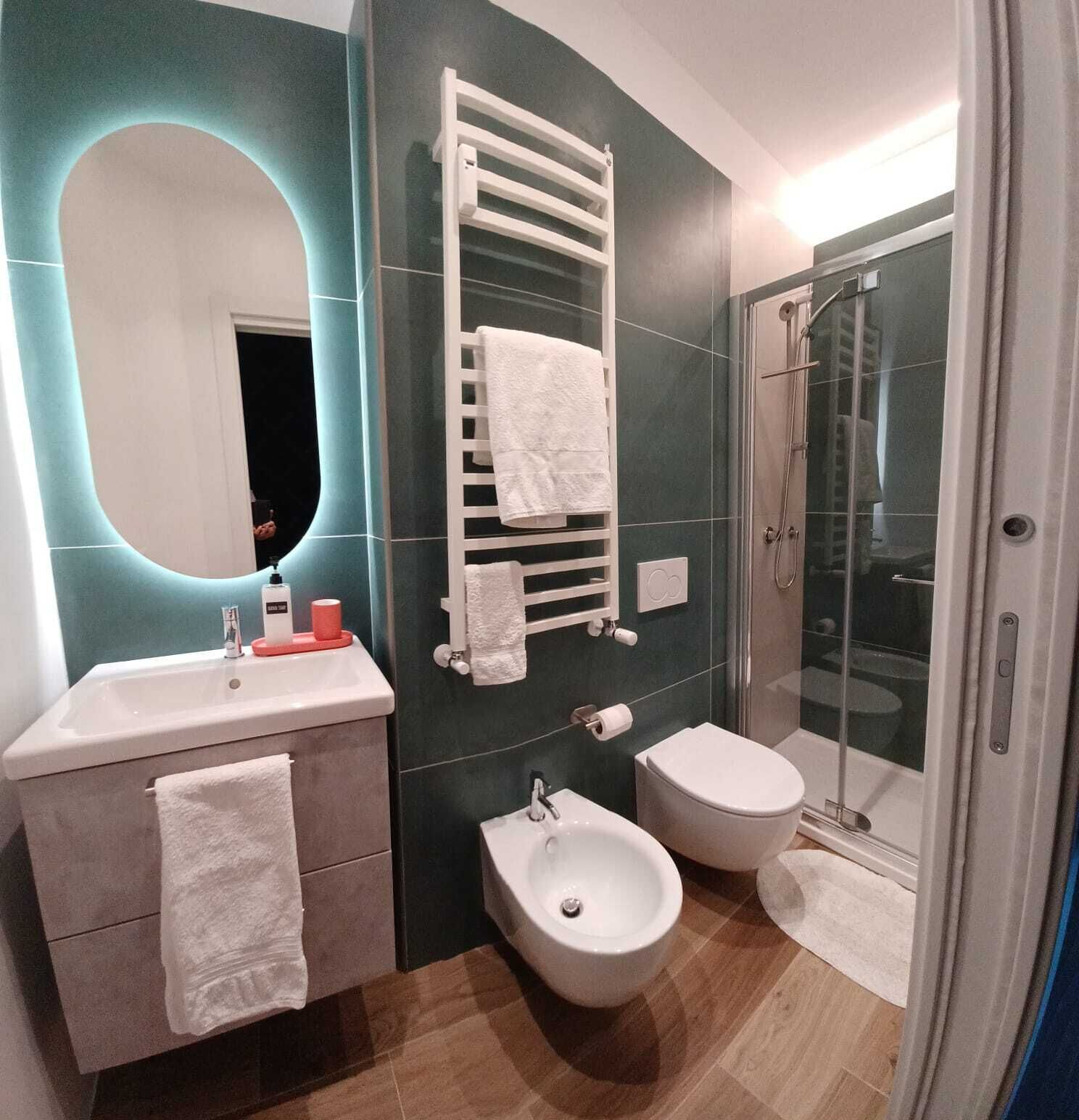 Een moderne badkamer met een wastafel, bidet, toilet en een douchecabine met glazen wanden.