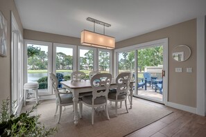 A dining area with a table and chairs, large windows, and a view of the outdoors. - 191 Twin Oaks at The Sea Pines Resort (Hilton Head Island)