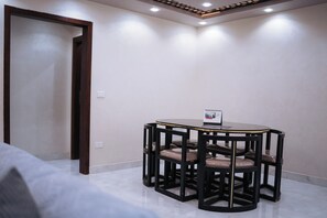 Ein Zimmer mit einem runden Tisch, vier Stühlen, einer Tür und einer Deckenleuchte.