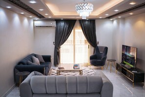 A modern living room with a sofa, armchair, coffee table, and TV stand.