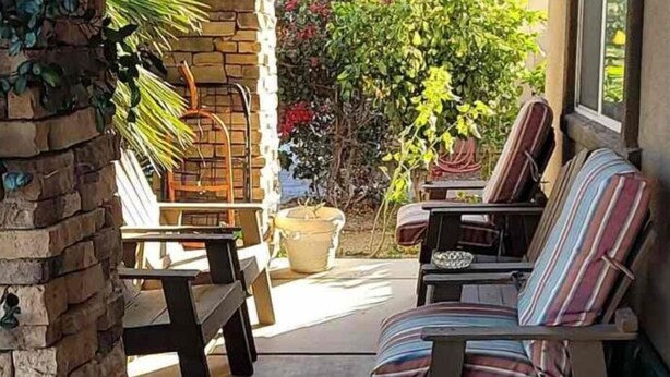 Een terras met een stenen muur, een barbecue en zitplaatsen buiten.