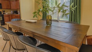 A dining area with a wooden table, six chairs, and a vase with green leaves. - Spacious Gem Near Fort Moore  (Columbus)