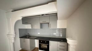 A compact kitchen with grey cabinets, a black countertop, and a built-in oven. - Mansfield City Centre - AvanteFirst (Mansfield)
