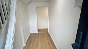 A narrow hallway with wooden flooring, white walls, and a door at the end. - Mansfield City Centre - AvanteFirst (Mansfield)