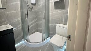 A modern bathroom with a glass-enclosed shower, a toilet, and a vanity with a mirror. - Mansfield City Centre - AvanteFirst (Mansfield)