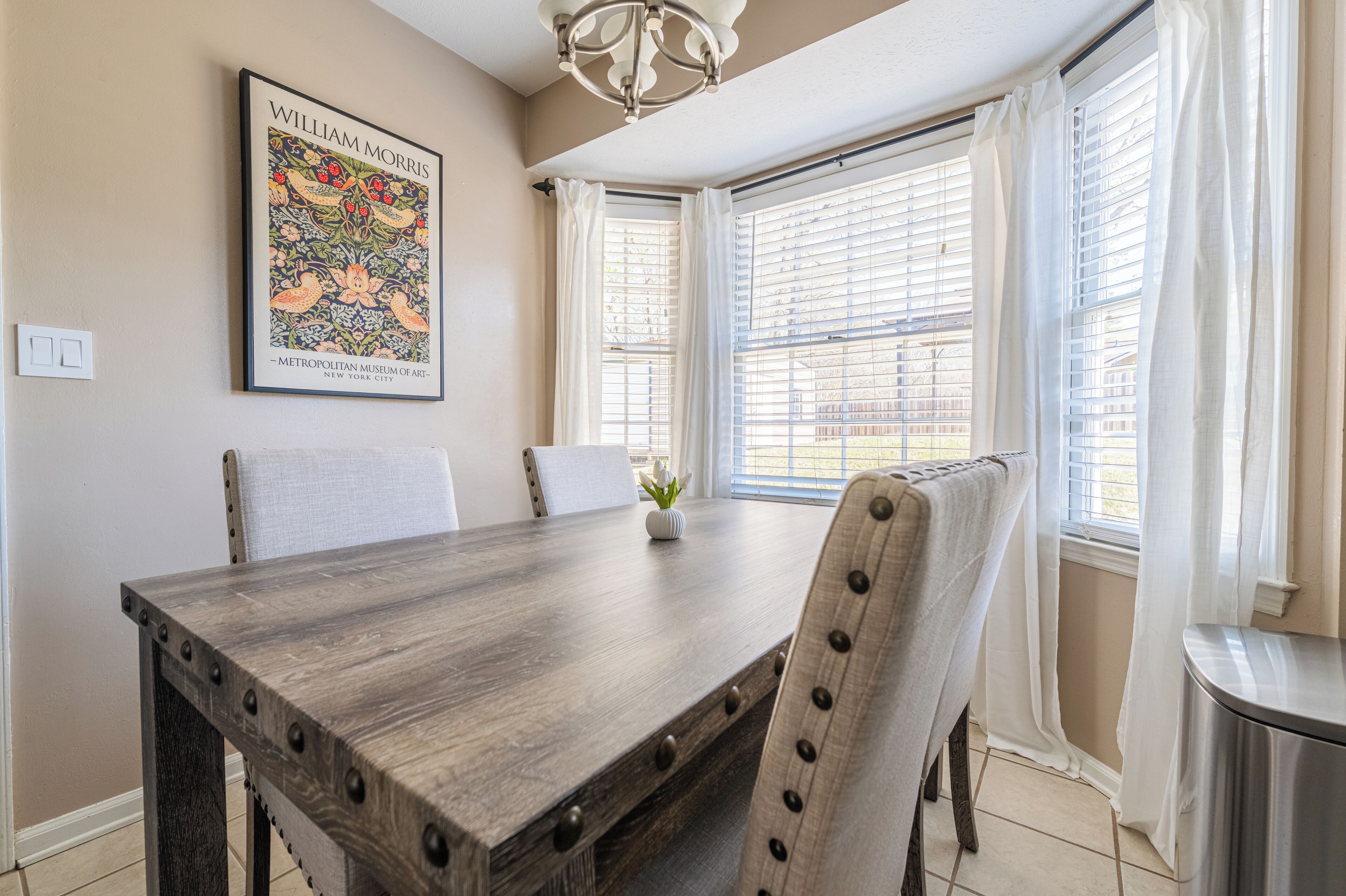 Un coin repas avec une table en bois, des chaises et un tableau encadré au mur.