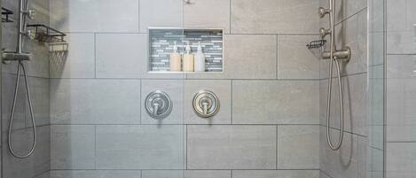 A walk-in shower with a glass door, tiled walls, and a hexagonal tile floor.