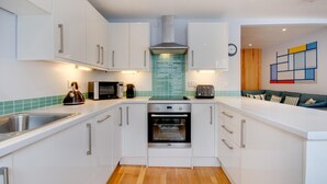 Een moderne keuken met witte kasten, een roestvrijstalen spoelbak, een inbouwoven en een magnetron.