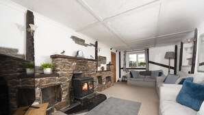 Una sala de estar acogedora con chimenea de piedra, un sofá y un televisor.