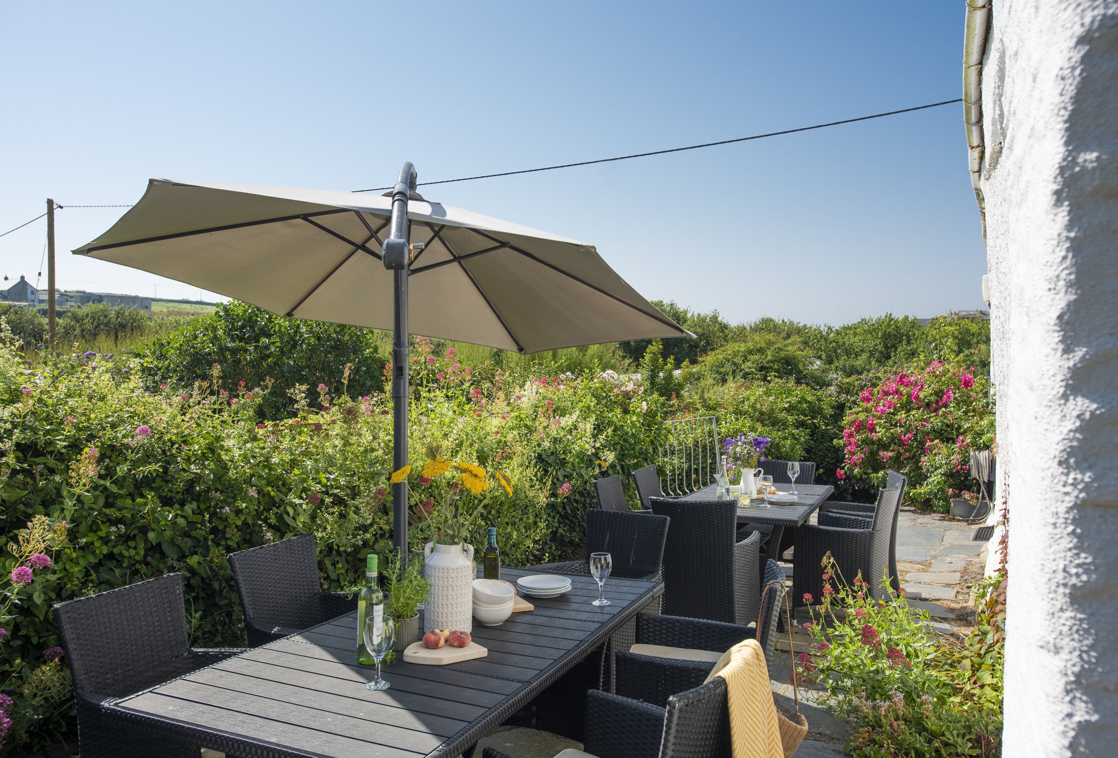 An outdoor patio with a table, chairs, and a large umbrella.