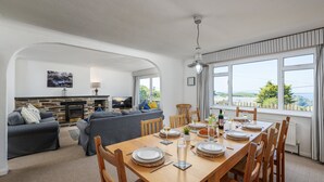 A dining area with a wooden table set for four, a fireplace, and a view of the outdoors. - Boskenna is a beautiful and spacious five-bedroom detached home (Tintagel)