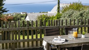 A wooden table with a newspaper, a glass of orange juice, and a bowl of nuts. - Boskenna is a beautiful and spacious five-bedroom detached home (Tintagel)