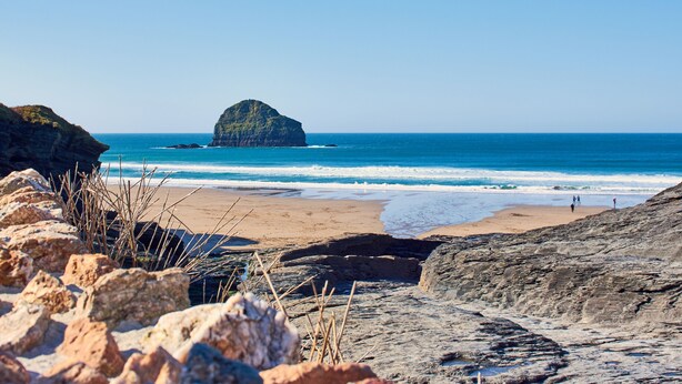 A rocky beach with a large rock formation in the distance, a sandy shore, and the ocean. - Boskenna is a beautiful and spacious five-bedroom detached home (Tintagel)