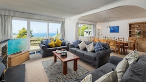 A spacious living room with a view of the sea, a dining area, and a kitchen.
