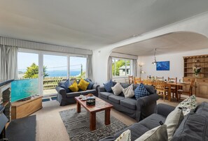 Amplia sala de estar con vista al mar, comedor y cocina.