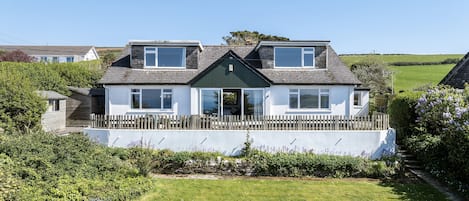 A two-story house with a white exterior, a wooden fence, and a grassy lawn.
