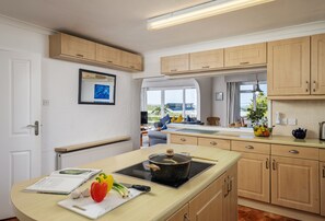 A modern kitchen with wooden cabinets, a built-in stove, and a window with a view.