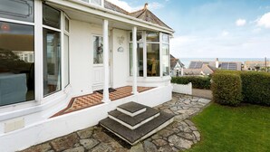 A white house with large windows, a stone staircase, and a view of the sea. - Welcome to Bay View, a stunning five-bedroom dog-friendly holiday home (Port Isaac)