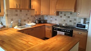 Une cuisine avec des meubles de rangement en bois, un évier, une cuisinière et un four à micro-ondes.