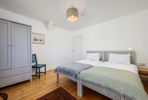 A bedroom with a bed, a wardrobe, a chair, and a painting on the wall.