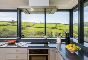 A kitchen with a large window offering a view of rolling hills.