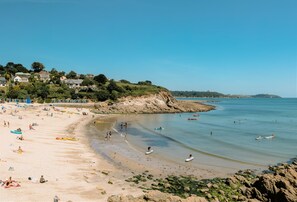 Ein Strand mit Menschen, Booten und Häusern im Hintergrund.
