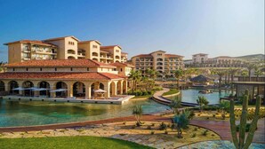Ein Resort mit mehreren Gebäuden, einem zentralen Pool und einer angelegten Fläche mit Palmen.