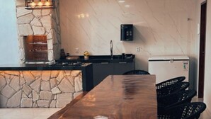Une cuisine moderne avec un îlot central en pierre, des chaises noires et un réfrigérateur encastré.