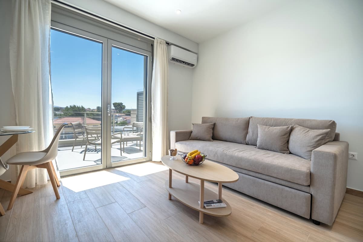 Uma sala de estar moderna com um sofá, uma mesa de centro com frutas e um espaço de jantar com uma cadeira e mesa.