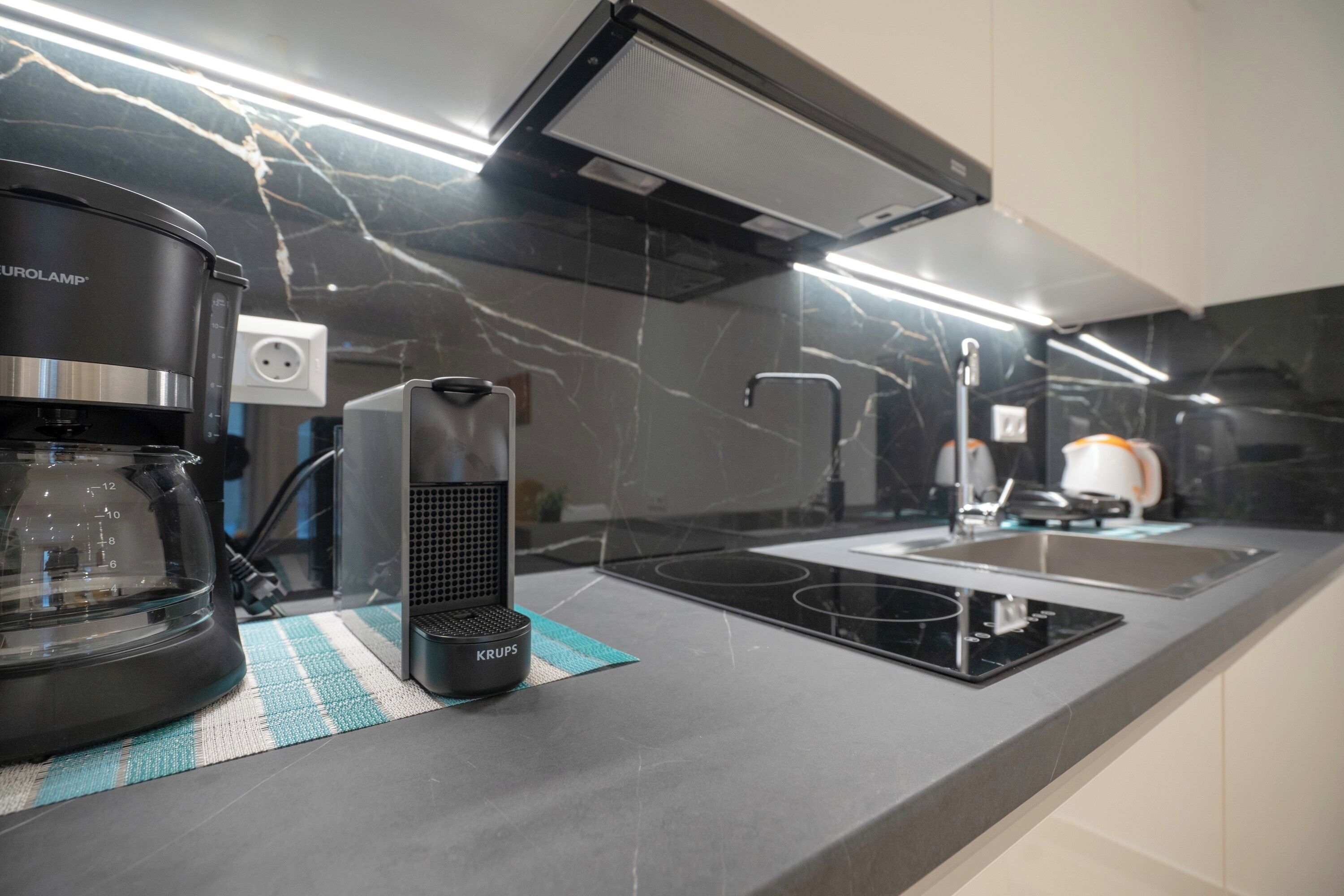 A modern kitchen with a coffee maker, Krups appliance, and a built-in stove.