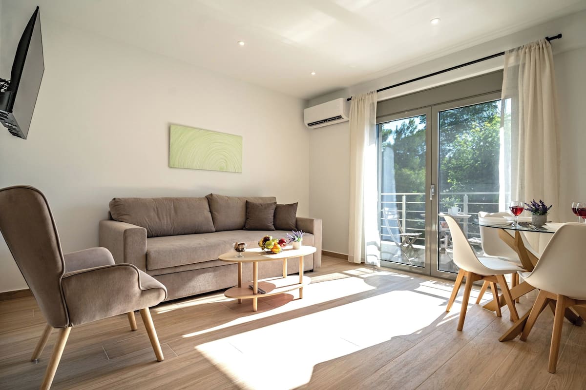 Uma sala de estar moderna com um sofá, uma mesa de centro redonda e um espaço de jantar com cadeiras e uma mesa de vidro.