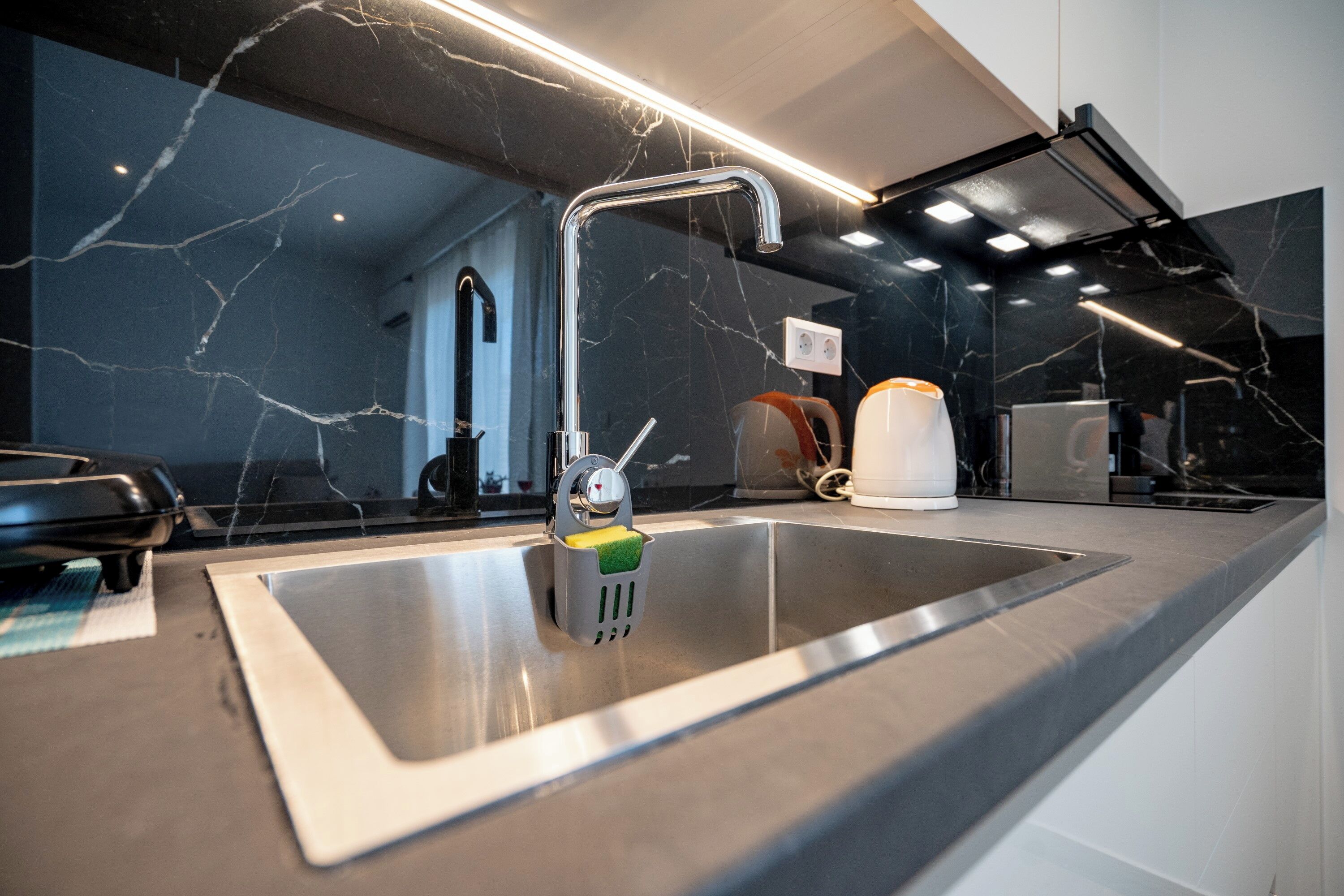 A modern kitchen with a stainless steel sink, a faucet, and a built-in oven.