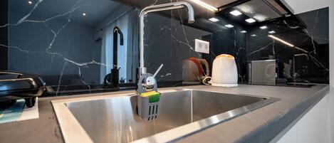 A modern kitchen with a stainless steel sink, a faucet, and a built-in oven.