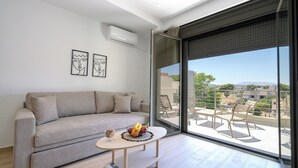 A modern living room with a sofa, a coffee table with fruit, and a balcony with outdoor furniture. - Arte 80 (Spata-Artemida)