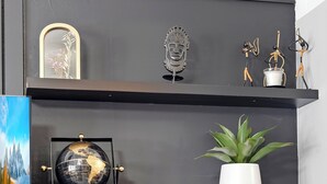 A modern room with a grey chair, a globe, and decorative items on shelves.