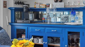 A kitchen with blue cabinetry, a coffee maker, and a sign that says "this is our happy place."