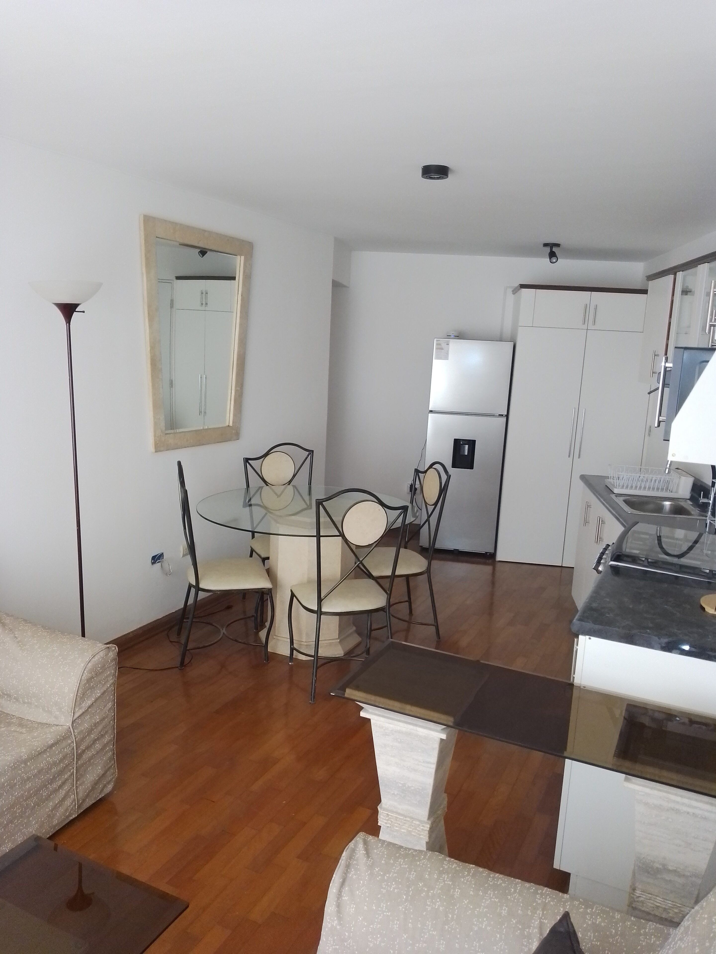 A compact living space with a dining area, kitchenette, and a large mirror.