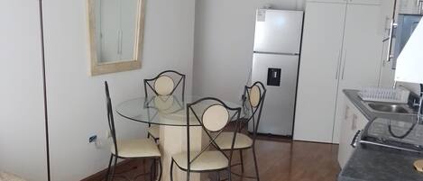 A compact living space with a dining area, kitchenette, and a large mirror.