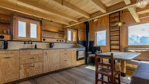 A wooden cabin interior with a kitchen, dining area, and a large window offering a view. - Gîte - HAUTELUCE - Alpine chalet (HAUTELUCE)