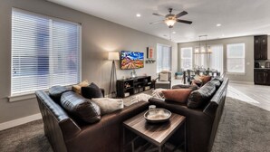 A modern living room with a sectional sofa, a coffee table, and a TV. - Entrada 611 | 4BR Luxury Townhome, Pool, Hot Tub, Garage (Moab)
