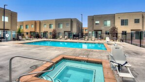A swimming pool with a diving board and lounge chairs, surrounded by modern buildings. - Entrada 611 | 4BR Luxury Townhome, Pool, Hot Tub, Garage (Moab)
