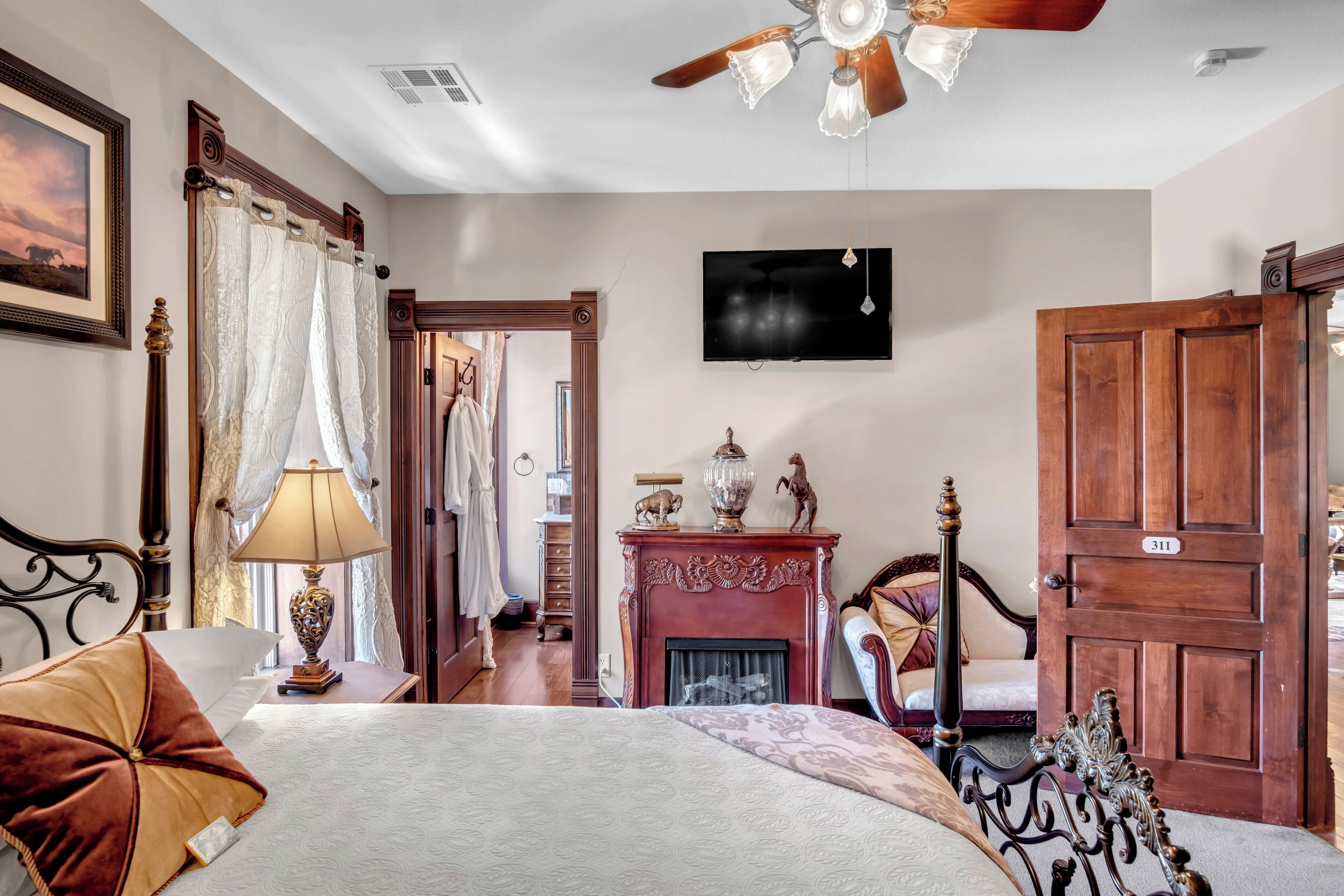 Un dormitorio con cama, chimenea, televisor y puerta de madera.