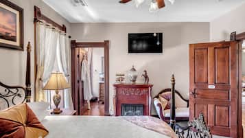 Un dormitorio con cama, chimenea, televisor y puerta de madera.