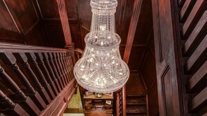 A grand staircase with a large, ornate chandelier hanging from the ceiling. - Historic Elgin Hotel (Marion)