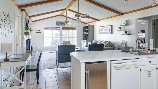 A spacious kitchen with a marble countertop, a dishwasher, and a dining area with a table and chairs.
