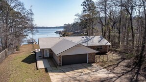 A single-story house with a garage, a covered patio, and a view of a lake.