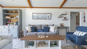 A living room with a sofa, coffee table, and a sign reading 'Southern Roots Lake House.'