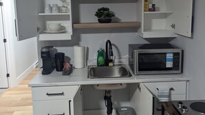 A compact kitchen with white cabinetry, a built-in microwave, a coffee maker, and a sink. - Cozy suite in a serene area (Magnetic Hill) near Casino in Moncton,NB (Moncton)