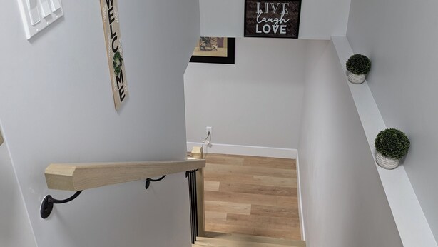 A modern staircase with a wooden finish, a wall-mounted light switch, and a 'WELCOME' sign. - Cozy suite in a serene area (Magnetic Hill) near Casino in Moncton,NB (Moncton)